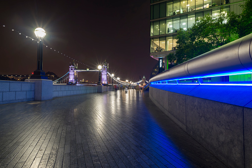 Night view of the Tower Bridge from the illuminated River Thames promenade at the More London Riverside area, Southwark, London,UK