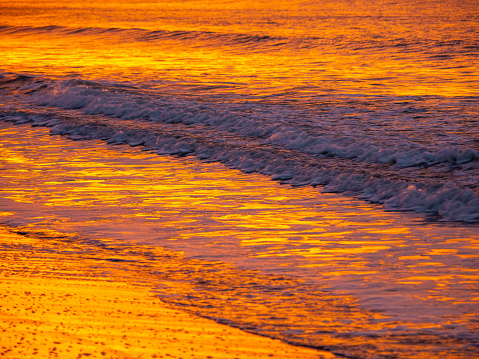 Sea waves along the seashore at sunrise in summer. Fiery sunrise or sunset