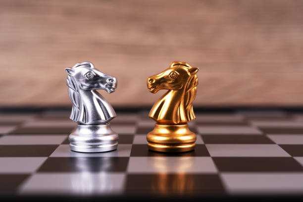 A pair of silver and gold chess knights facing each other.