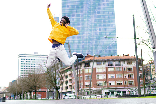 Vibrant african young man jumps high with happiness in the city.
