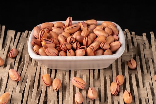 large grained Siirt pistachios. Siirt pistachios have larger grains than pistachios. The peanuts pouring into the nuts plate were shot in a studio environment with a full frame camera.