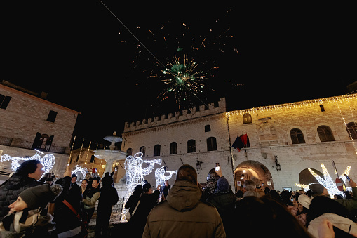Assisi, Italy - January 1, 2024: people partying in the main square of the city for New Year's Eve at night with fireworks and a concert