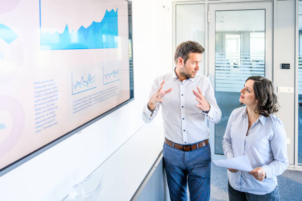 istock Colleagues talking in front of a screen with a graph 2071302073