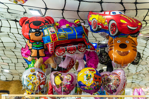 Saint-Petersburg, Russia - 5 January 2024. A bunch of balloons with cartoon characters on them, including a train, a car, a bear, a monkey, and a tiger