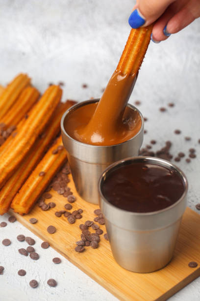 istock Person Dips Churros Into Cup of Chocolate 2071316633
