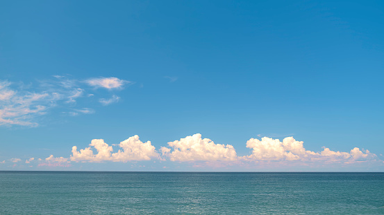 Blue sky with white clouds over the horizon of the blue sea