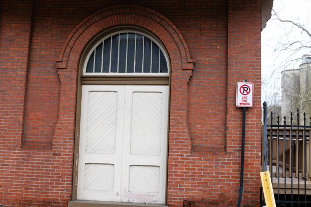 Historic red brick structure with white door decorative door and arched window, landscape, outdoors, daytime, winter, copy space, stock image