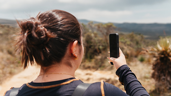 Individual using a smartphone to document the expansive beauty of Colombia's paramo region