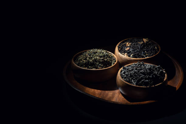 Tea leaves in wooden bowls shot in low key stock photo