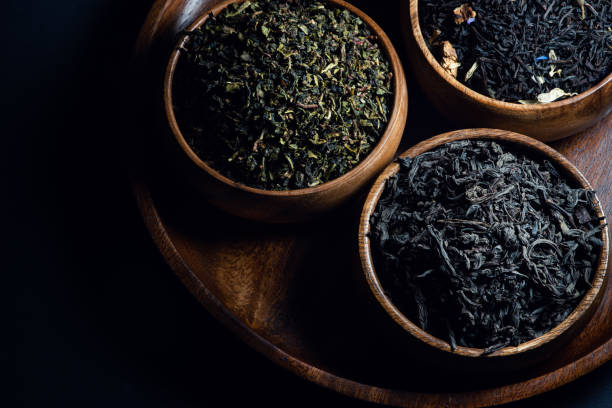 Tea leaves in wooden bowls shot in low key stock photo