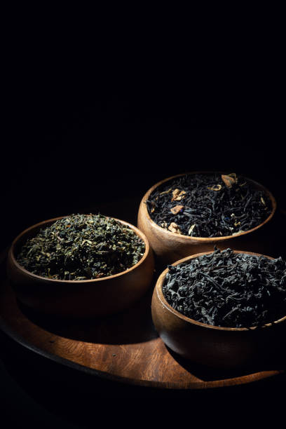 Tea leaves in wooden bowls shot in low key stock photo