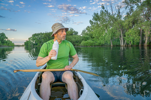 senior male paddler in a decked expedition canoe on a calm lake in northern Colorado