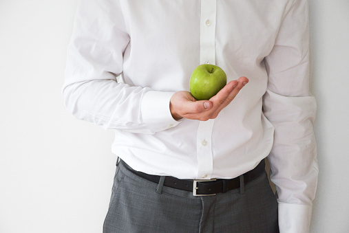 Businessman in shirt and suit holding a green apple