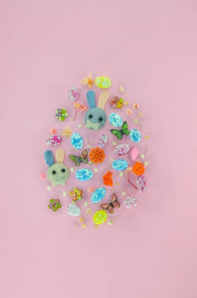 Creative Easter egg made with colorful candies, wooden buttons, flowers on pastel pink background. Flat lay Easter concept