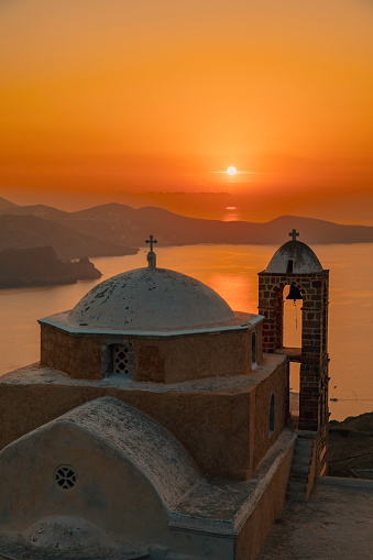 sunrise view on the roof next to the bell tower and dome of the Traditional Greek Orthodox Cycladic church in Plaka Village on Milos Island, Greece. Milos is one of the southern Cyclades islands in the Archipelago