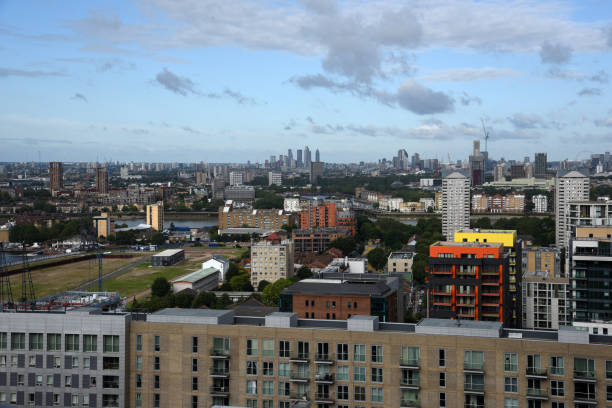 London Cityscape with the Canary Wharf business district. The image shows several tall business buildings with cloudy sky, captured during summer season.
