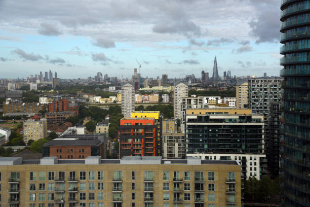 London Cityscape with the Canary Wharf business district. The image shows several tall business buildings with cloudy sky, captured during summer season.