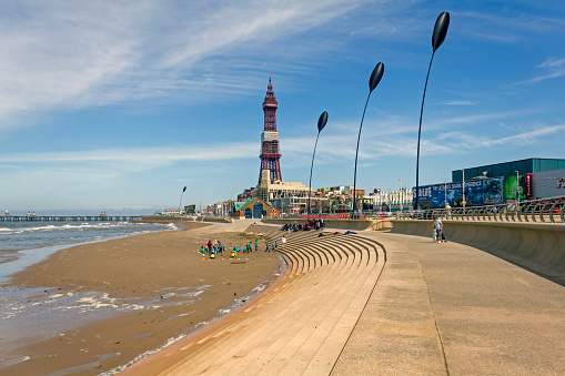 View along the promenade at Blackpool, UK.  Blackpool tower can be seen in the distance and people can be seen on the beach