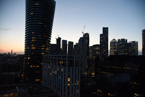 London Cityscape with the Canary Wharf business district. The image shows several tall business buildings, captured during summer season at dusk.