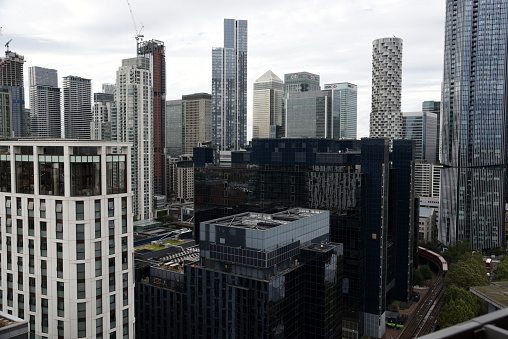London Cityscape with the Canary Wharf business district. The image shows several tall business buildings with cloudy sky, captured during summer season.