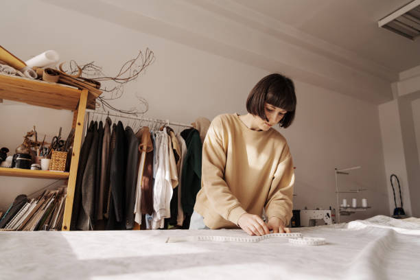 istock Creative woman measuring fabric in bright sewing studio 2071488203
