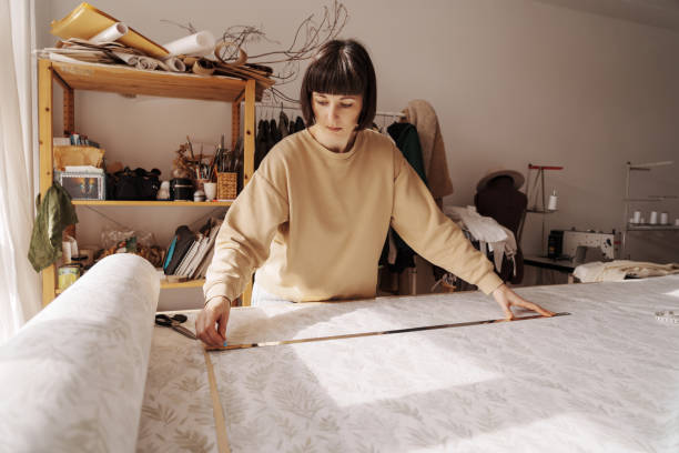 istock Creative woman tailor measuring fabric in sunlit workshop 2071488213
