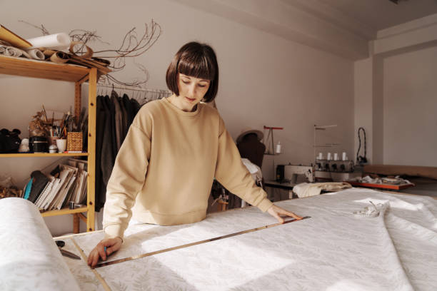 istock Focused woman measuring fabric in her sewing studio 2071488215