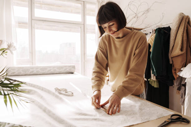 Female fashion designer working in bright sewing studio