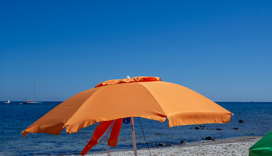 Horizontal closeup photo of sections of two white fabric outdoor dining umbrellas with aluminium frames with a section of clear blue Summer sky in between.