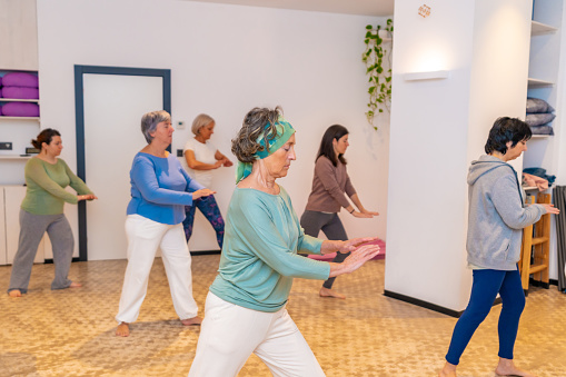 Mature women in a Qi gong class choreographing the exercises moving coordinated