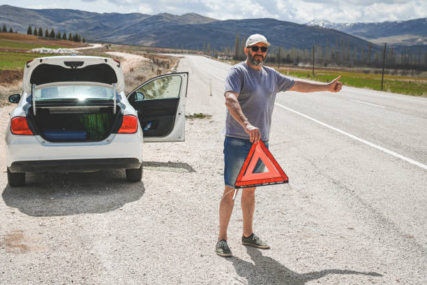 man stands by a broken car - stranded travel people traveling disappointment - fotografias e filmes do acervo