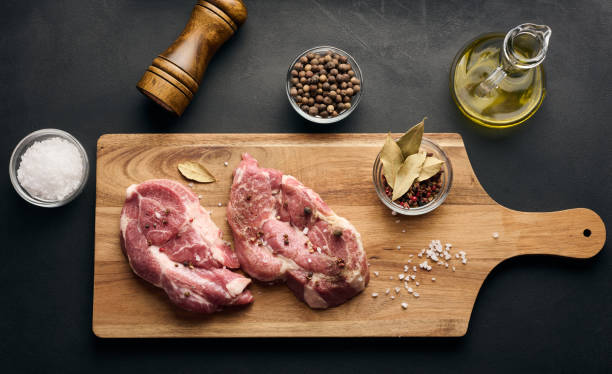 istock Two raw pork neck steaks on a board and spices for cooking. Top view 2071658965