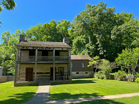 Mitchell, Indiana, USA - June 20, 2022:  Historic Upper Residence in the recreated and restored 1800 Pioneer Village at Spring Mill State Park, near Mitchell, Indiana with beautiful green grass copy space.