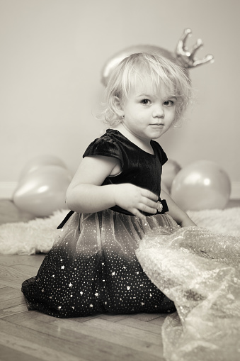 Two years old pretty little girl posing on wooden floor for portrait