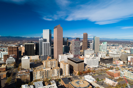 Aerial view of the skyline of downtown Denver with Rocky Mountains in the background.