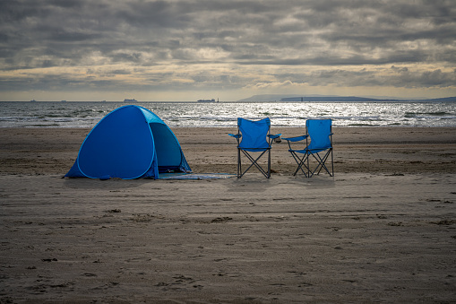West Wittering, West Sussex, England, UK - October 03, 2022: Two camping chairs and a tent on the beach