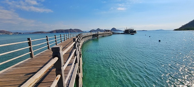 Labuan Bajo, Indonesia - Sept 22, 2023: Picture of piers on green turquoise calm sea water with arid hills and blue sky as the background