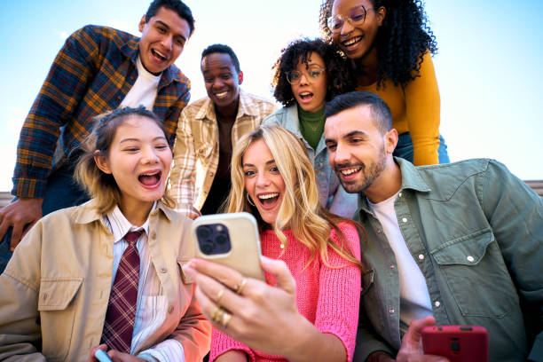 istock A group of happy amazed humans friends in outerwear using mobile smiling watching something funny 2071849301