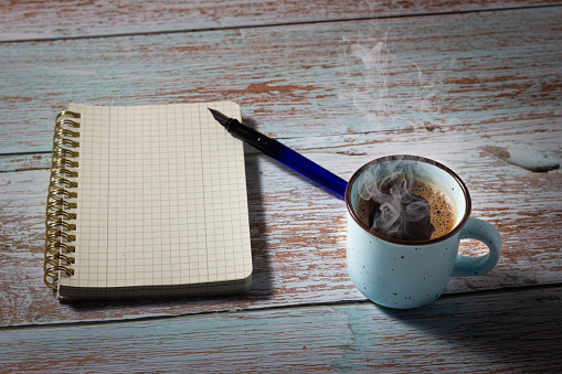 Creation process with a notebook, a fountain pen and a cup of freshly brewed coffee. Concept of creativity.