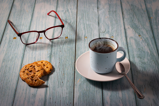 Cup of aromatic coffee and cookie on wooden background.