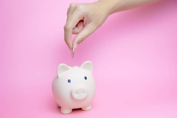 istock A woman's hand is inserting coins into a piggy bank. 2071923600