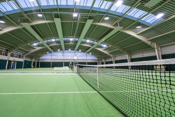 Empty green tennis courts under roof.