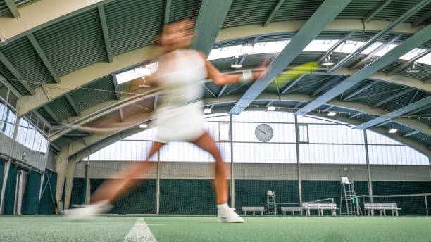 Blurred female tennis player hitting ball with racket in court, wide shot long exposure