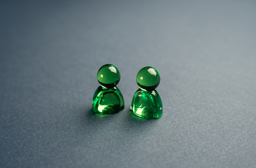 Two green glass figures of people. Concept of communication and business relationship. Assistance, cooperation and collaboration. A meeting. Friendly relations. Communication and discussion.