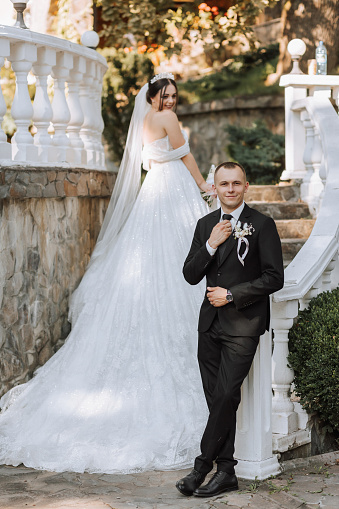 Full-length portrait of bride and groom on garden steps, groom in foreground