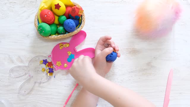 Child making funny Easter eggs from colorful plasticine. Handmade. Concept of children's creativity, crafts for kids.