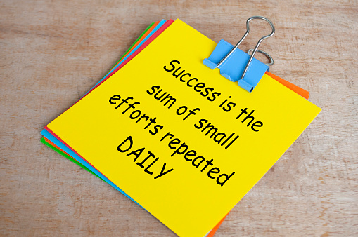 Success is a sum of small efforts repeated daily text on yellow notepad. Encouragement concept