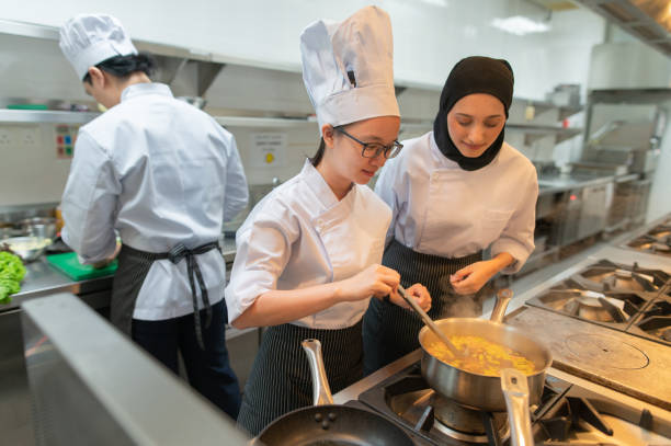 los aprendices de cocina llevan a cabo su ámbito en la cocina - hygiene food chef trainee fotografías e imágenes de stock