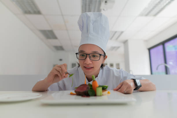 Asian female kitchen apprentice decorate the food before serve to customer