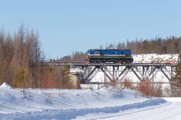 Diesel locomotive on the railway bridge in the winter forest